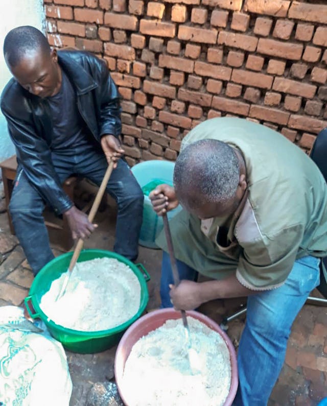 En esta fotografía se ve a un educador sanitario enseñando a los miembros de la comunidad a hacer una mezcla nutritiva de harina.