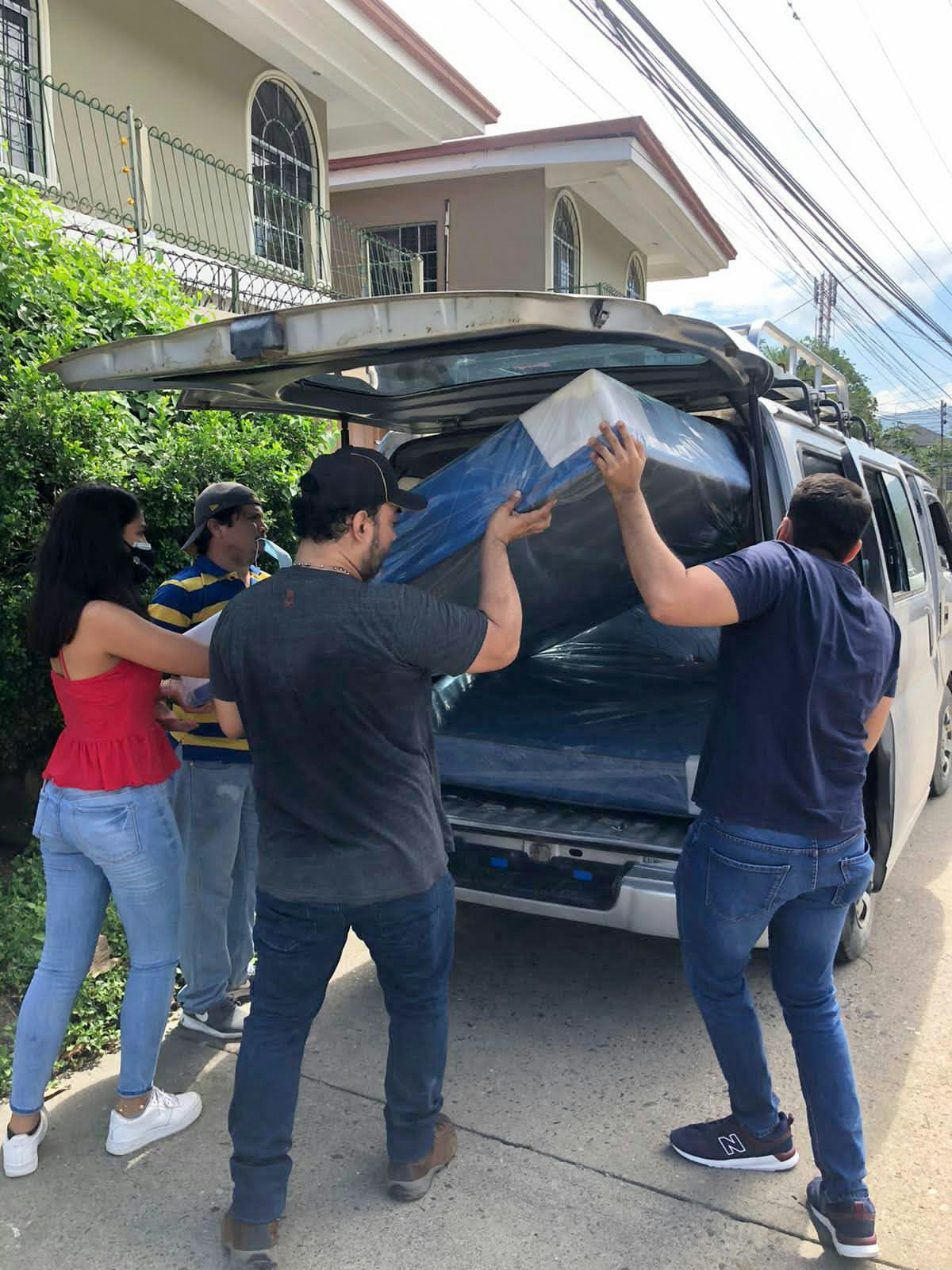 Voluntarios coordinados por el comité de emergencia transportan colchones donados para familias de la ciudad de San Pedro Sula, duramente afectada, donde muchas personas han perdido sus casas.