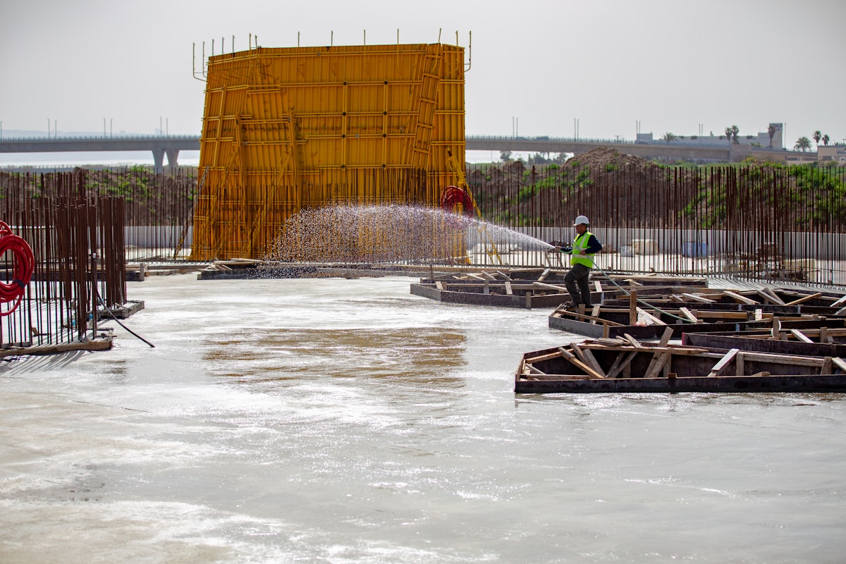 Une fois que le béton du sol de la place aura pris, la construction des murs plissés autour de la place et des piliers de l’édifice principal pourra commencer.