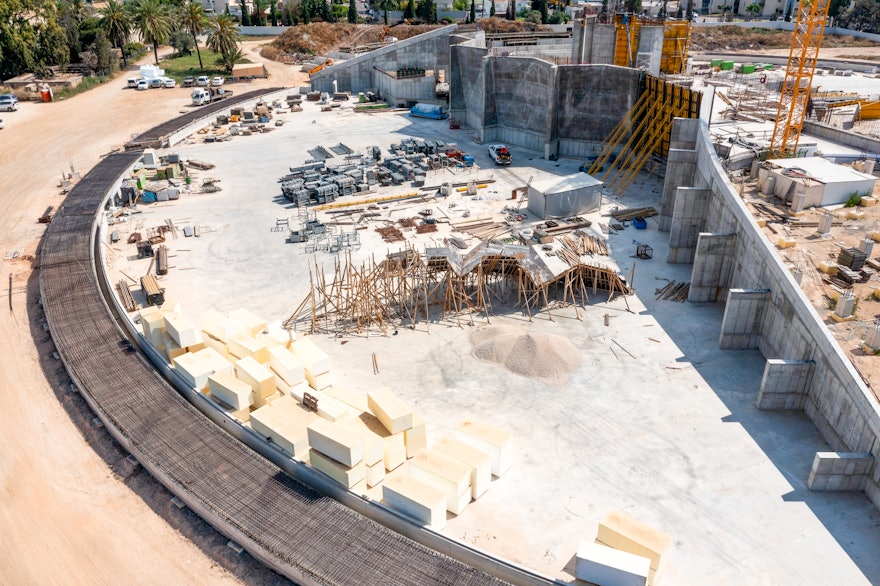 El conjunto completo de muros en forma de pliegues se conecta con uno de los muros del portal de la plaza sur. A la izquierda de esta imagen, también se ven los cimientos construidos para el sendero que rodeará el santuario. El espacio entre el sendero y los muros se rellenará con una berma de jardín inclinada.