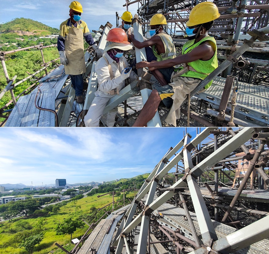 Workers position the steel elements of the structure with great precision while a surveyor provides directions from ground level.