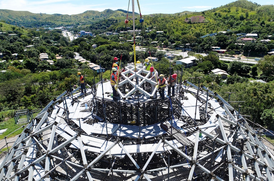 Construction workers raise the first of nine steel units of the dome into position.
