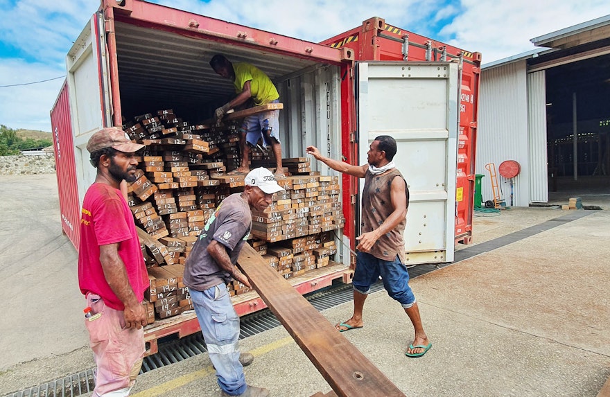 Des ouvriers déchargent une cargaison de bois recyclé qui recouvrira le dessous de chaque auvent d’entrée et se poursuivra à travers les murs intérieurs de l’édifice central.