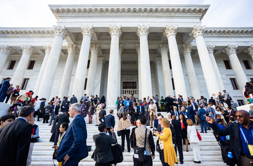 Los participantes reunidos en los escalones de la Sede de la Casa Universal de Justicia antes de entrar en el vestíbulo para el inicio del programa.