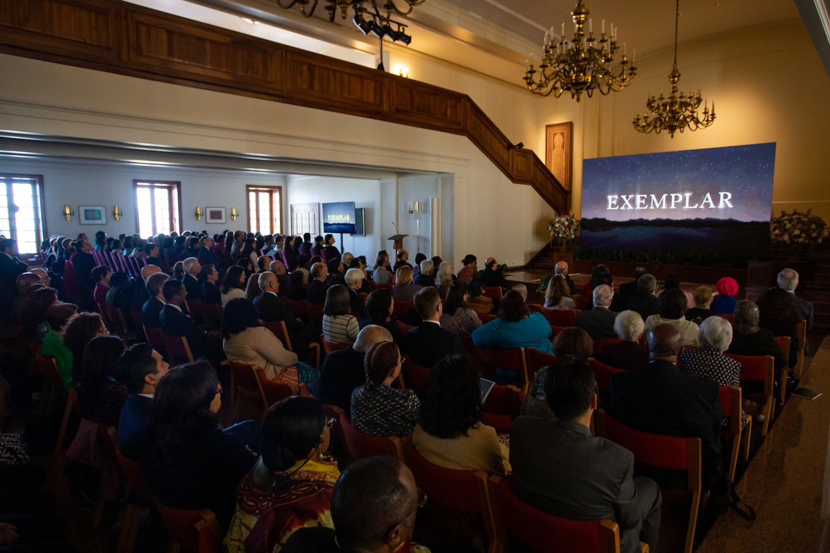 Les participants regardent le film  L'Exemple , lors d’une projection dans le hall du siège de la Maison universelle de justice.