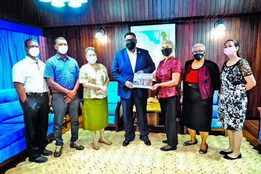 The President of Guyana, Irfaan Ali, receiving a book about ‘Abdu’l-Bahá from members of the Bahá’í National Spiritual Assembly of that country.