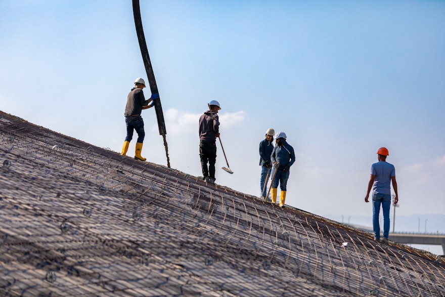 Concrete is pumped onto the slope of the berm.