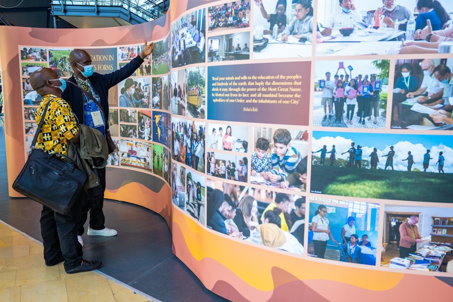 Two of the participants at the 13th International Bahá’í convention discuss a section of the exhibition which shows ongoing efforts around the world towards the promotion of spiritual and moral education.