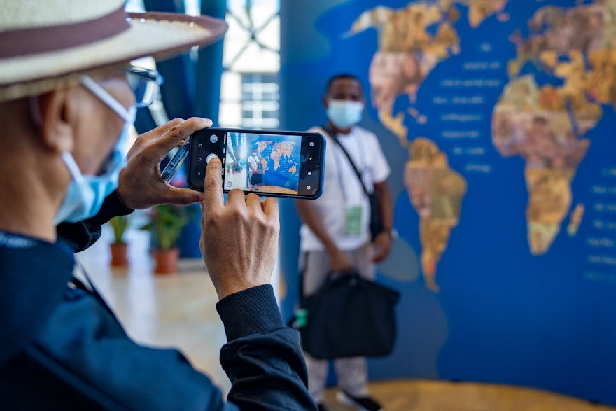 A delegate standing by an exhibit showing various efforts of the Bahá'í community around the world to contribute to social betterment.