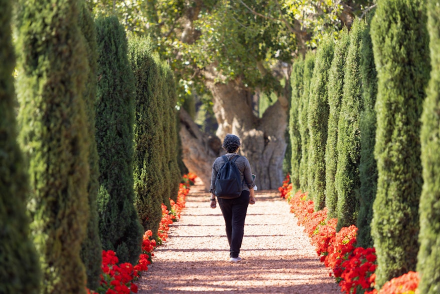 A delegate walks along a path outside of the Shrine of Bahá'u'lláh.