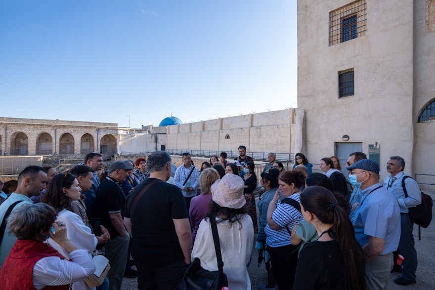 Groupe de délégués dans la cour de la citadelle. La fenêtre supérieure derrière eux se trouve dans la section de la prison où Bahá'u'lláh et sa famille étaient enfermés.