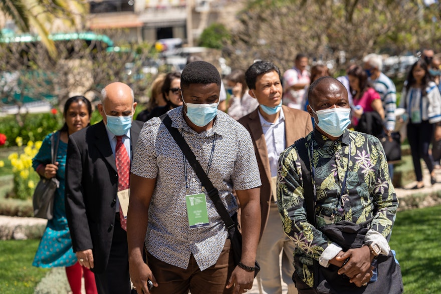 Convention participants from countries including India, Myanmar, the Philippines, and Sierra Leone approach the former Pilgrim House near the House of ‘Abdu’l-Bahá.