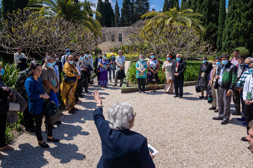 Un groupe de participants à la Convention de différents nationalités écoute un guide devant l’ancienne maison des pèlerins, près de la maison de ‘Abdu’l-Bahá.