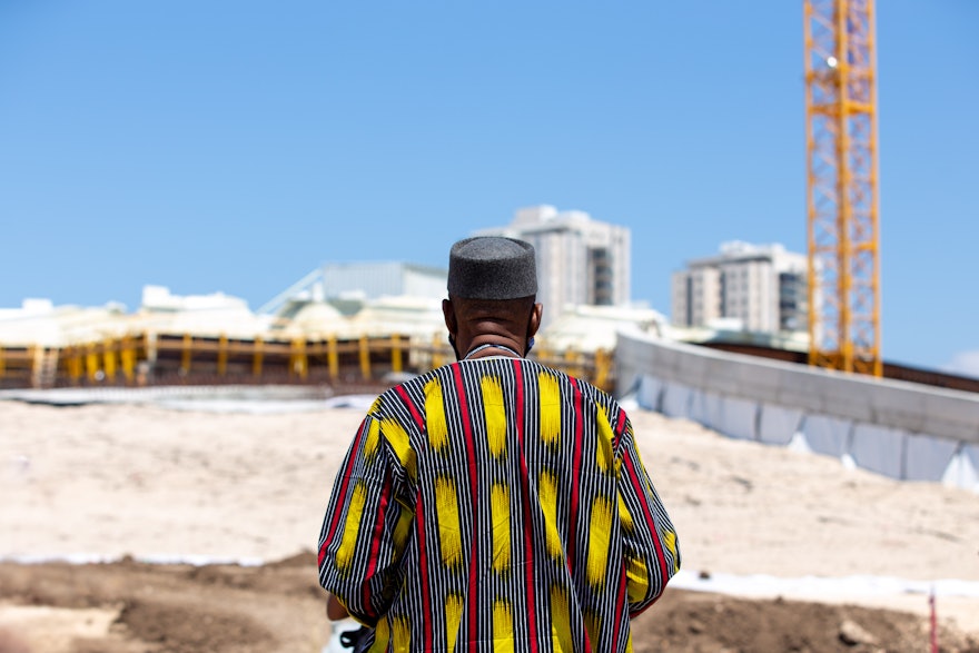 Un délégué se tient devant la berme ouest du chantier de construction du mausolée de ‘Abdu’l-Bahá.