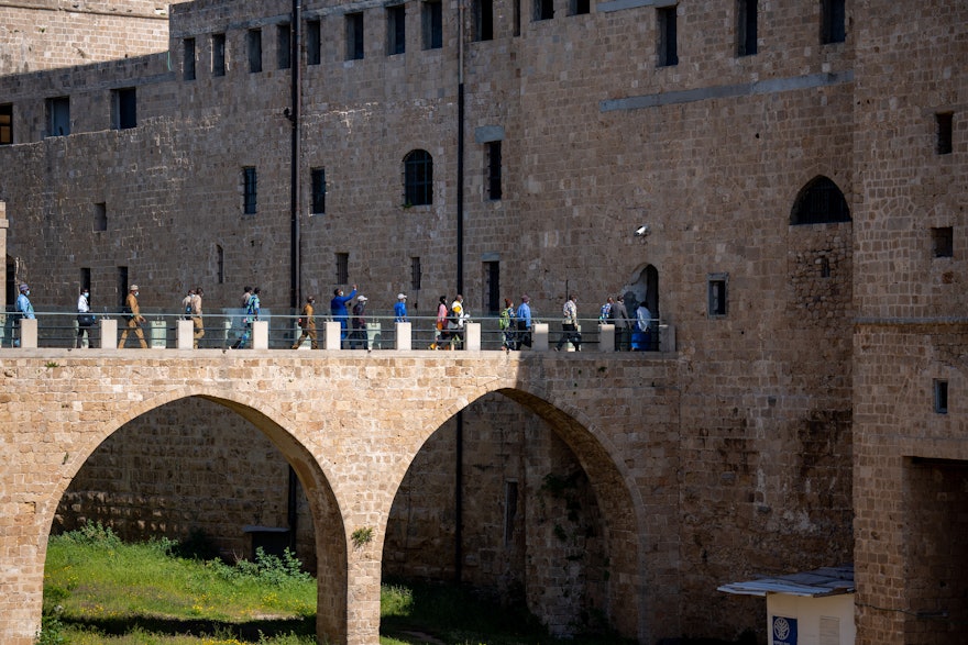 نمایندگان در ابتدای بازدید از سلول زندان، از خندقی که شهر قدیمی عکا را احاطه کرده است عبور می‌کنند.