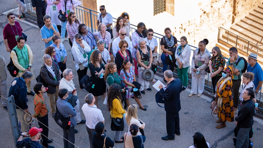 Des délégués réunis dans la cour de la citadelle d’Acre écoutent un guide lors de leur visite de la cellule de la prison.