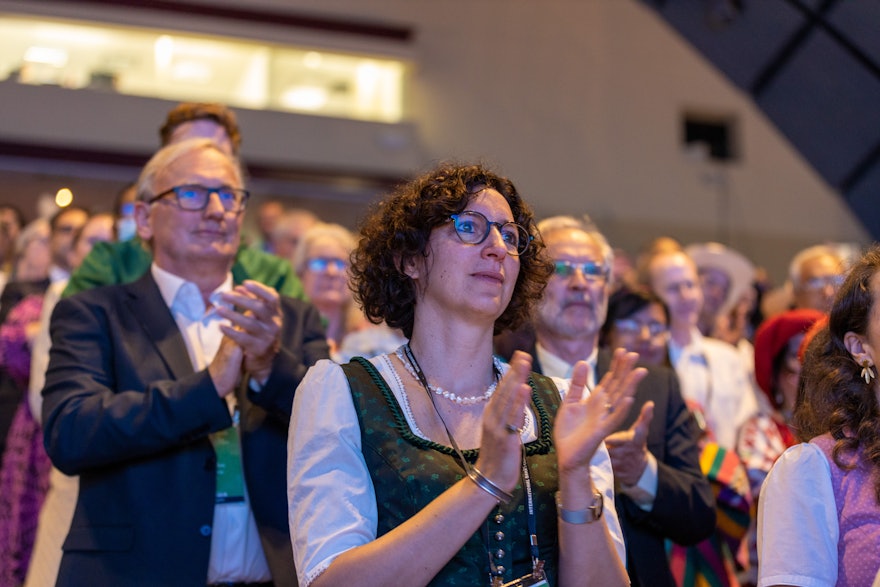 Una delegada aplaude de pie durante las primeras sesiones de la XIII Convención Internacional Bahá’í