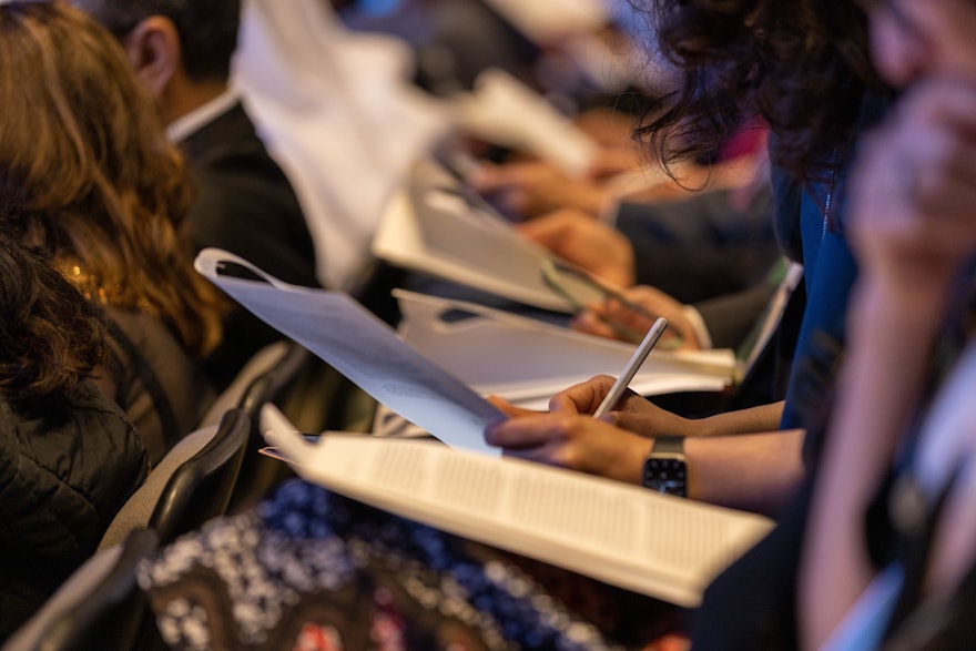 A delegate takes notes while the Riḍván message of the Universal House of Justice is read aloud during the morning session.