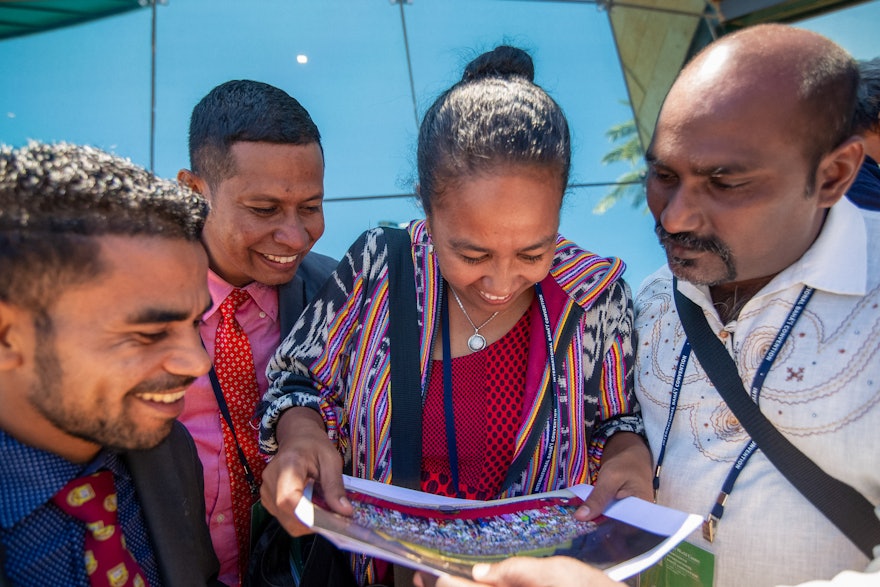 Representantes de Timor Oriental contemplan la foto oficial de grupo de la XIII Convención Internacional Bahá’í