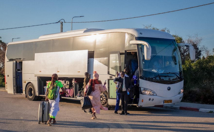 Los participantes suben a un autobús con destino al aeropuerto tras la celebración del Día Sagrado en Bahjí