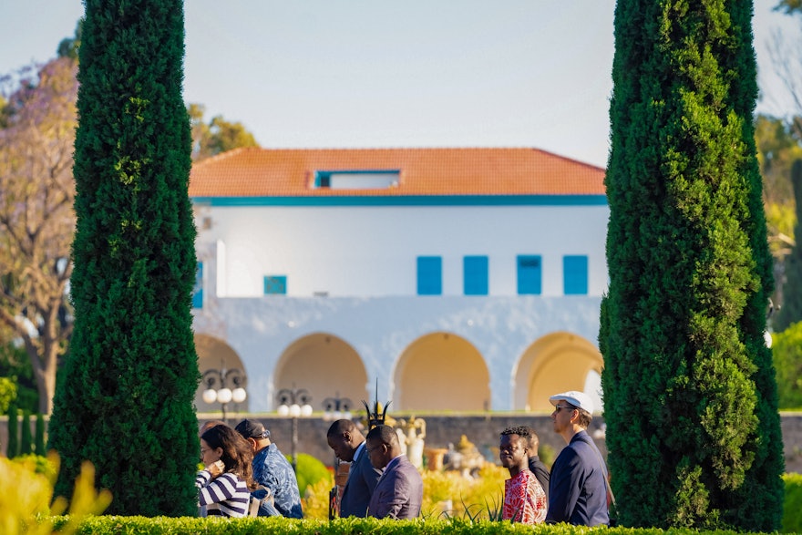 La mansión de Bahjí puede verse a lo lejos mientras los participantes de la Convención circunambulan el Santuario de Baháʼu’lláh