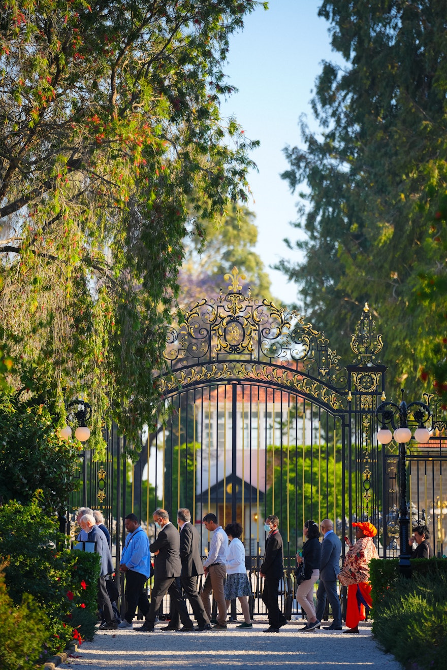 Los participantes de la Convención caminan junto a la Puerta Collins mientras circunambulan el Santuario de Baháʼu’lláh