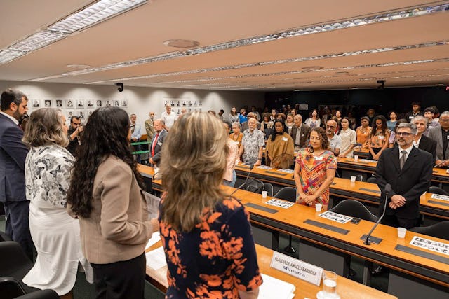 Participants stand for a minute of silence called for by Federal Deputy Erika Kokay of the lower house of Congress.