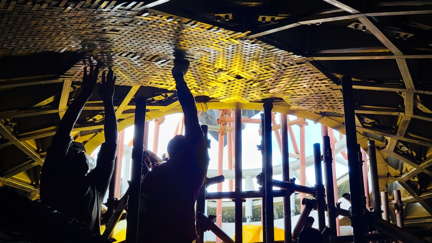 Esta imagen muestra otra vista del interior donde los trabajadores están instalando esteras trenzadas alrededor del óculo de la cúpula.