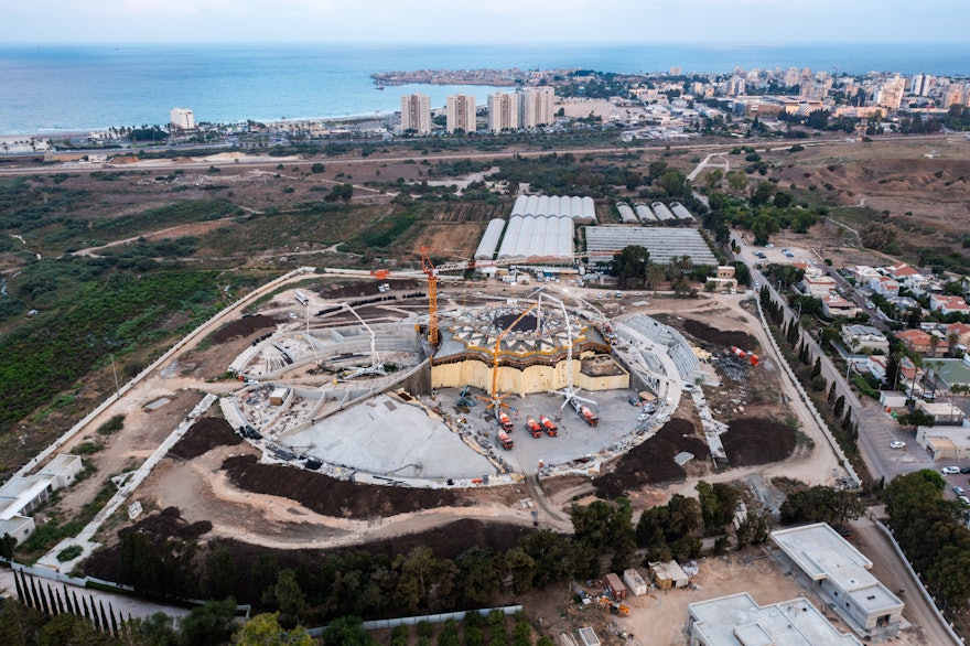 Late Sunday afternoon, the concrete trucks are just beginning to pour the grey concrete. The city of ‘Akká can be seen in the distance.