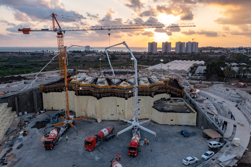 The sun sets on Sunday evening with work fully under way to cast the roof structure. The base of the east berm is used as a staging area for two of the concrete pumps.