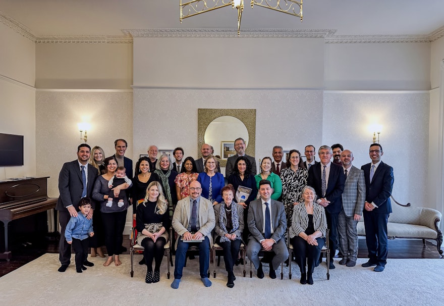 عکس دسته‌جمعی از اعضای محفل روحانی ملی بهائیان انگلستان، تیم معماران و سایر مهمانان در مراسم افتتاحیه آپارتمان مرمت شده شماره ۱۷ در خیابان رویال یورک کرسنت بریستول.