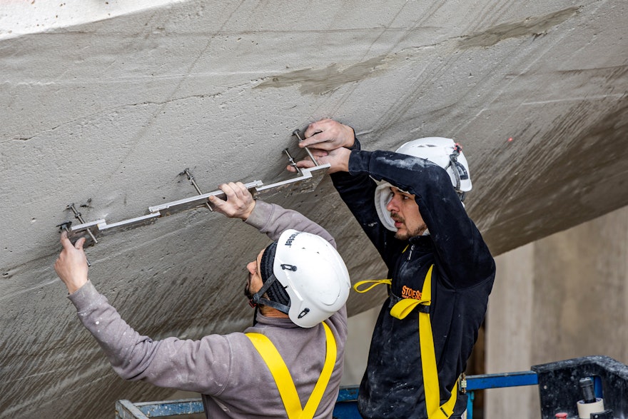 Workers begin by installing a metal frame into the concrete under the trellis in preparation for installation of the marble.