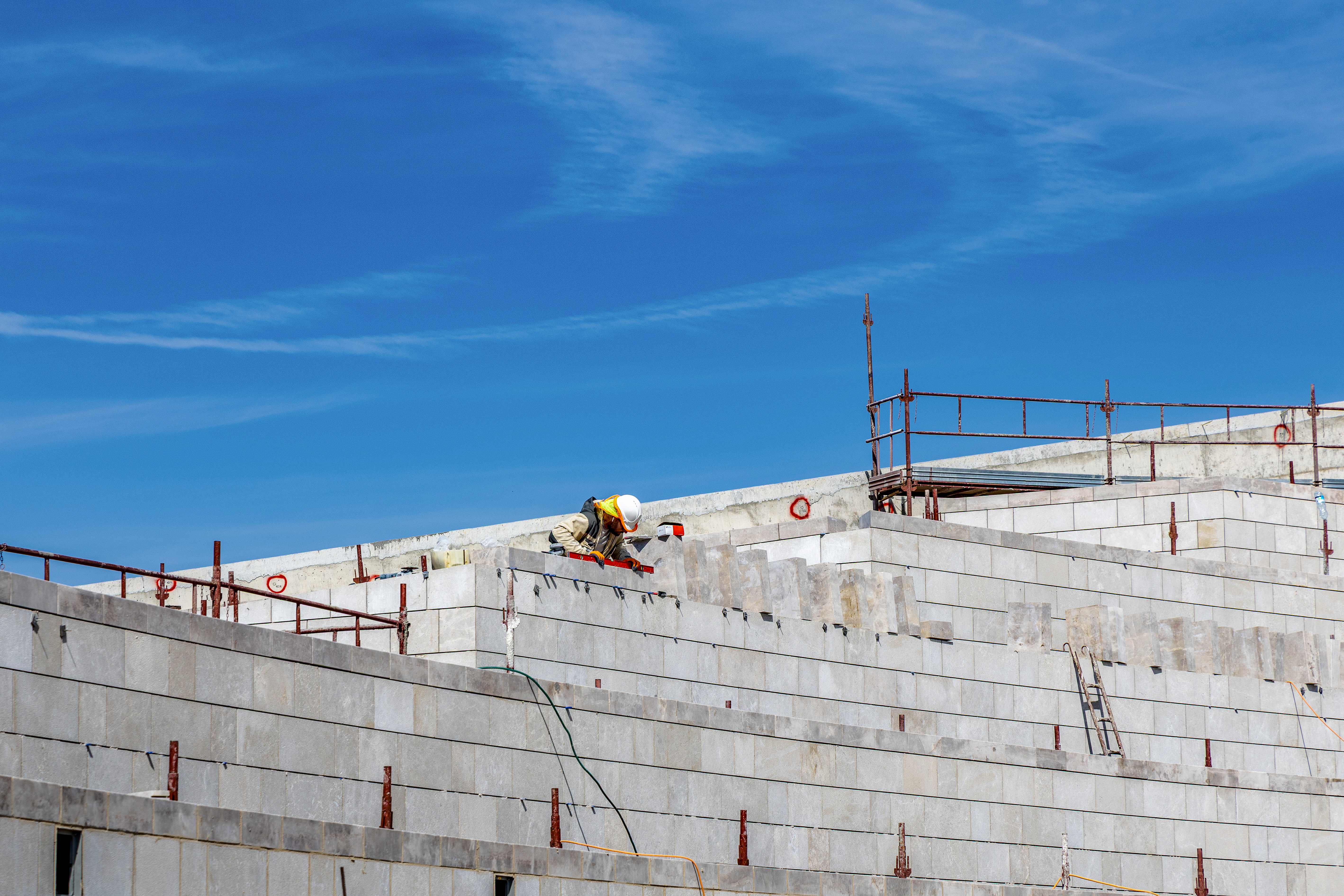 Local stone being placed on the walls of the garden planters in the south plaza.