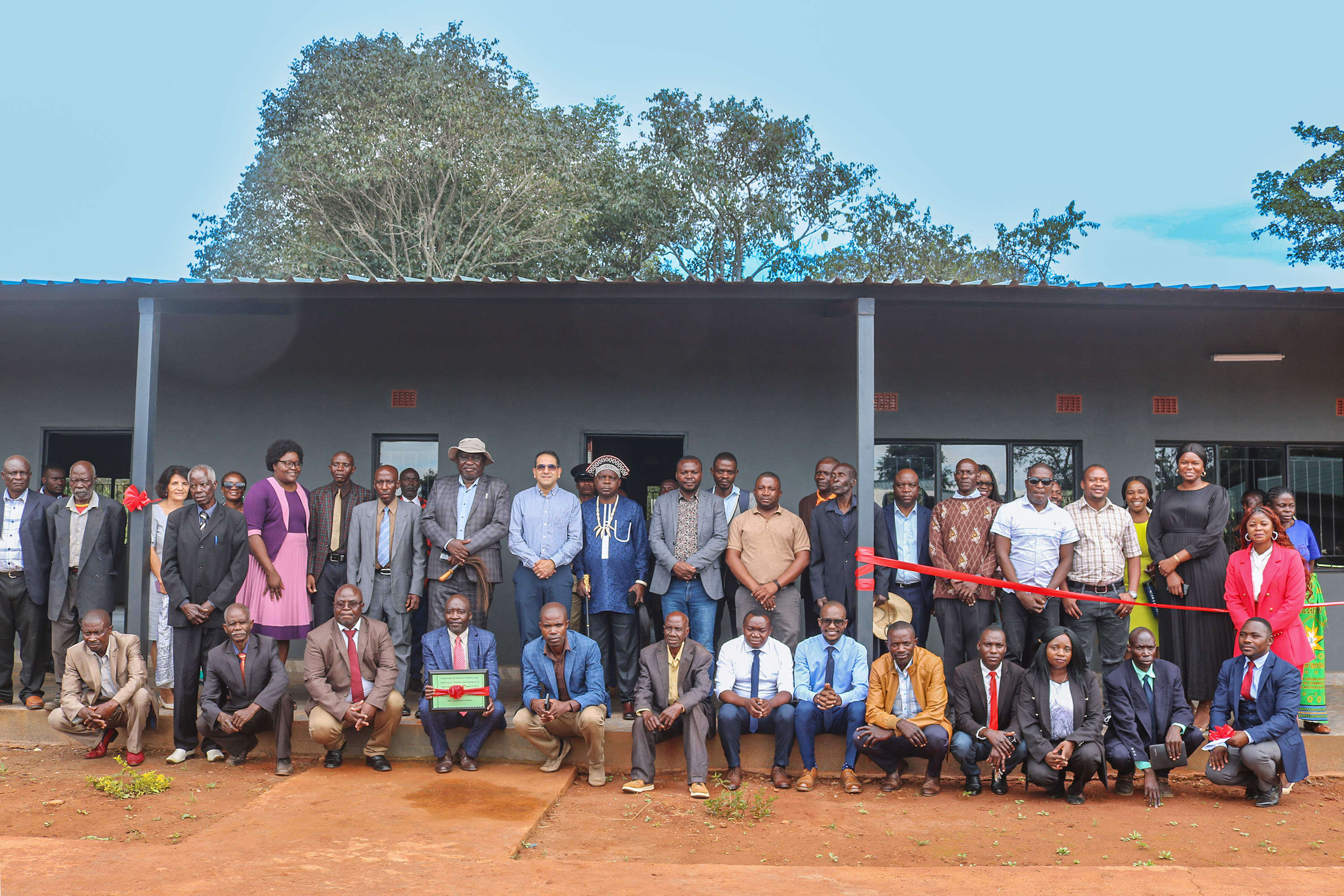Members of the Bahá’í Local Spiritual Assembly, traditional leaders, including two senior chiefs, government representatives, and community members gathered at the opening of the new school in Katuyola. 