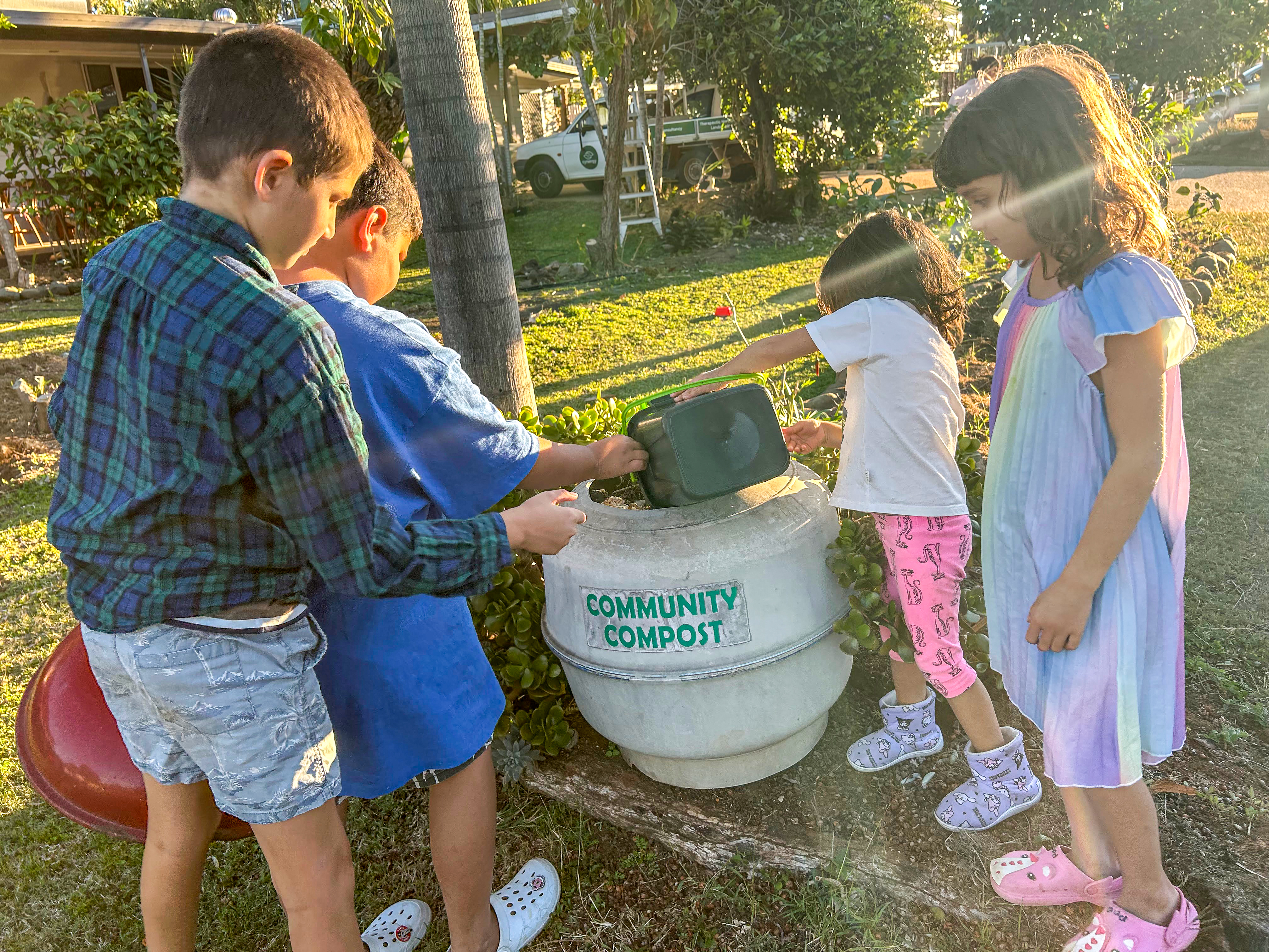 Les enfants participent à des activités de compostage dans le jardin communautaire où les familles apportent leurs déchets alimentaires et partagent les récoltes.