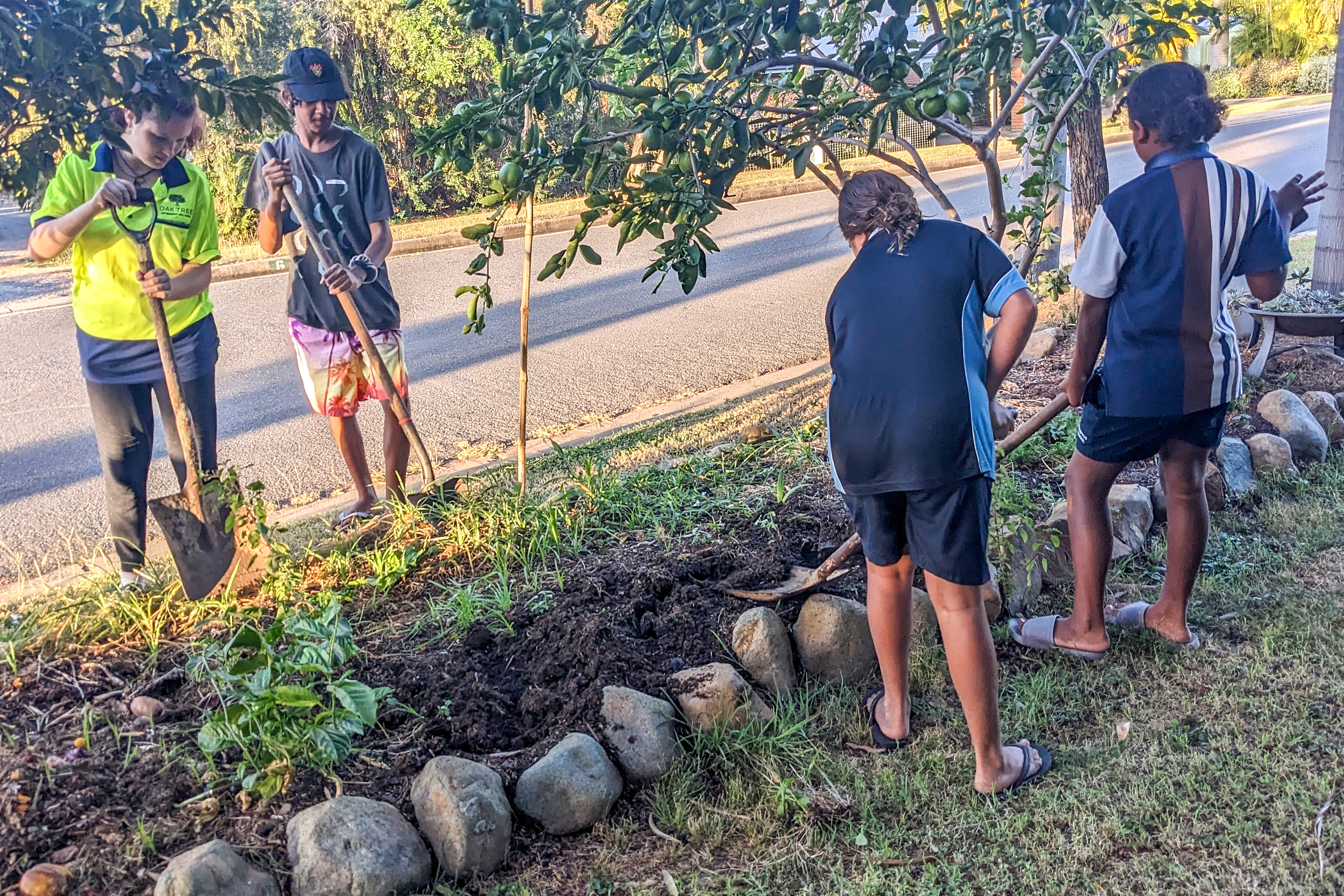 Des jeunes s’occupent d’un jardin de quartier situé en bordure de rue à Gracemere, une initiative communautaire lancée en 2016 pour favoriser la biodiversité locale et offrir un espace où les familles collaborent et s’entraident.