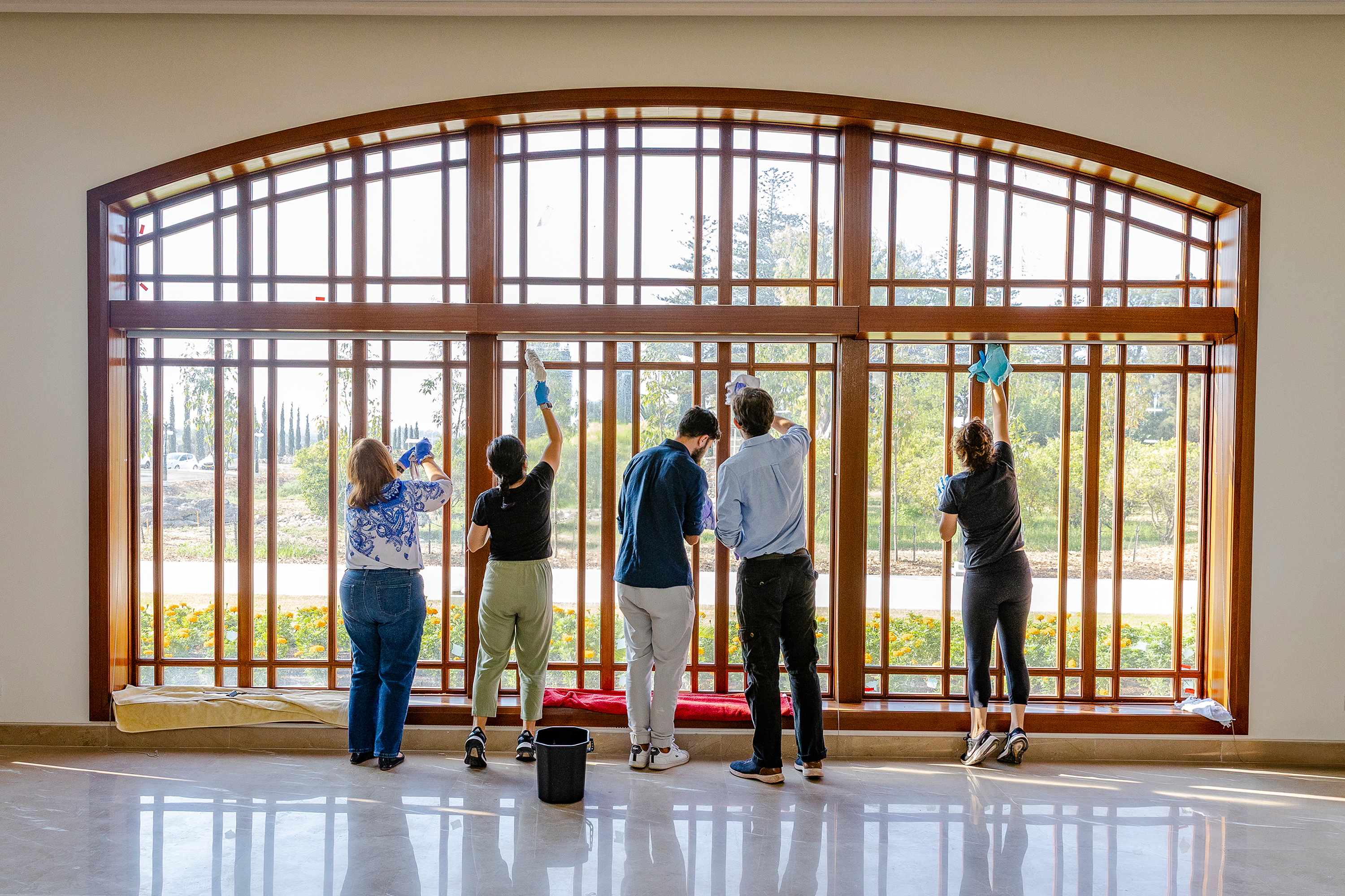 Volunteers serving at the Bahá’í World Centre cleaning windows of the main hall of Visitors’ Centre.