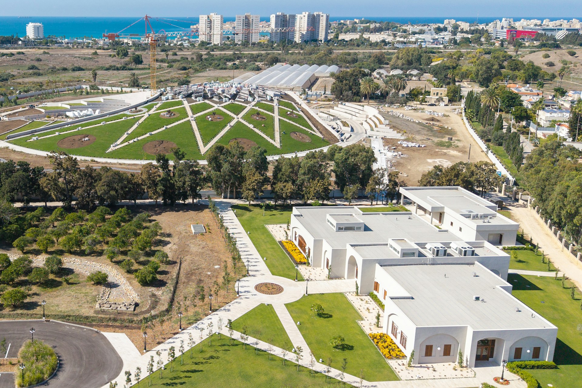 The paths leading towards the ‘Akká Visitors’ Centre have been carefully considered in the site’s design. Upon entering the site, visitors will initially take a path, seen in the image extending from the bottom left, toward the centre courtyard where they will catch their first glimpse of the Shrine across the landscaped berm to the west.