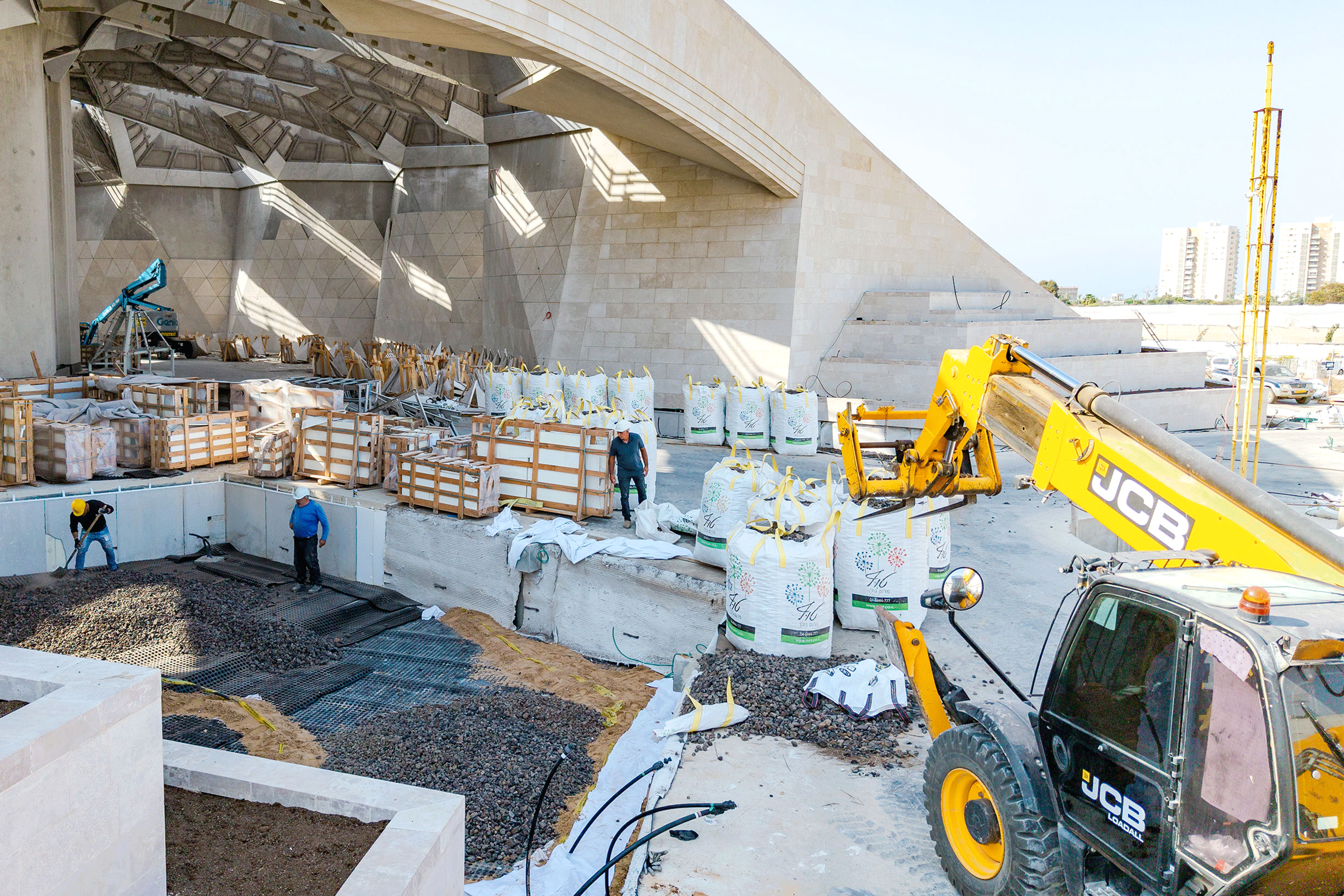 Workers preparing landscaping materials for planters that have yet to be constructed.