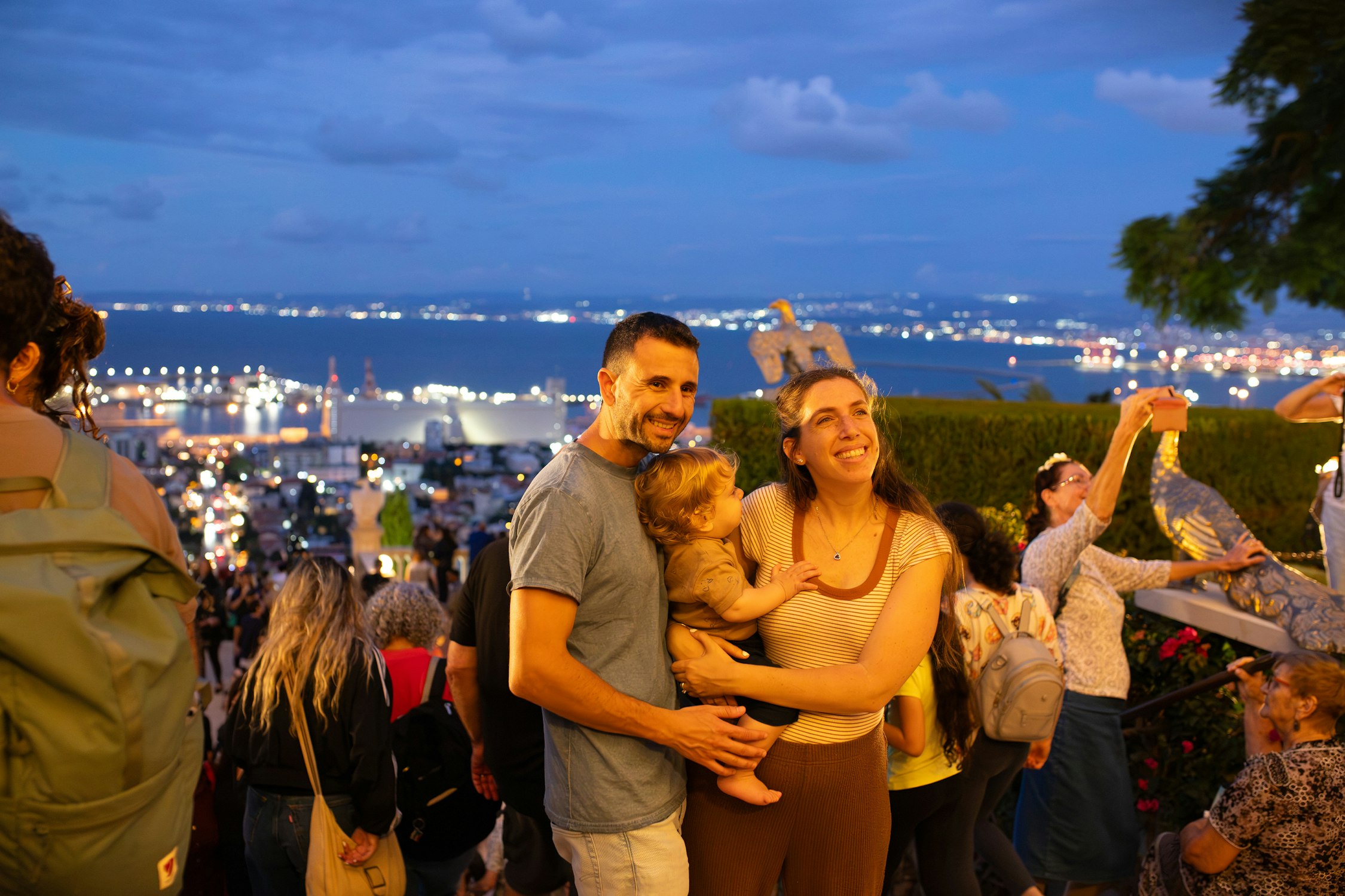 Une famille profitant d’une soirée ensemble dans les jardins illuminés du tombeau du Báb.