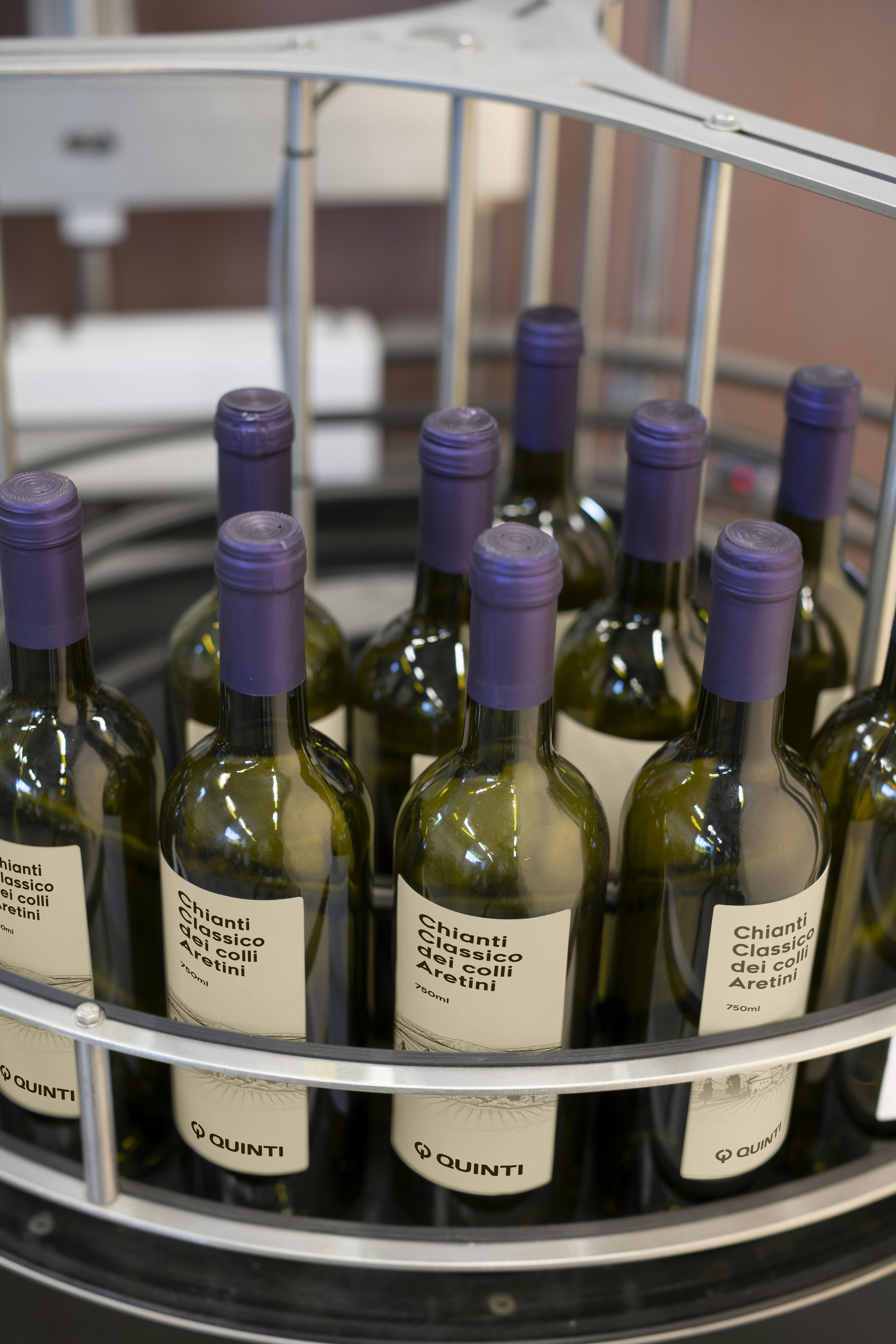 Una tavola indicata per l'accumulo di bottiglie, in questo caso vi sono collocate delle bottiglie di vino con capsula viola ed etichetta personalizzata Quinti