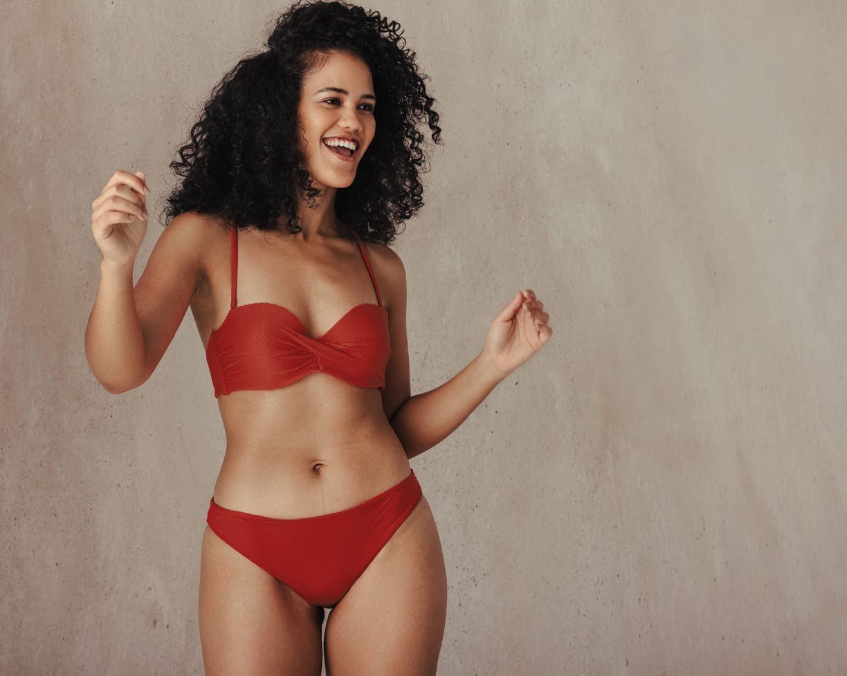 Woman with curly hair, smiling while wearing a bikini