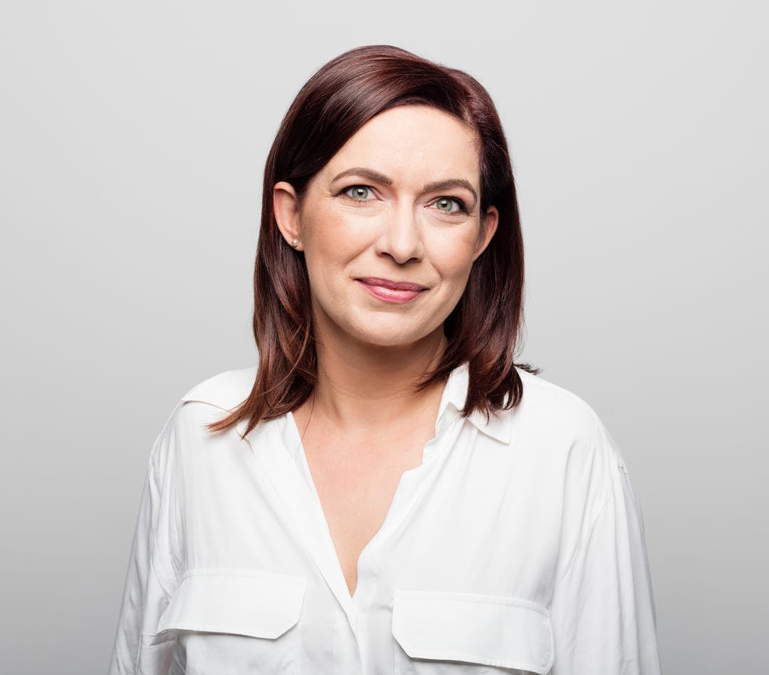Woman with burgundy hair wearing a white button up shirt
