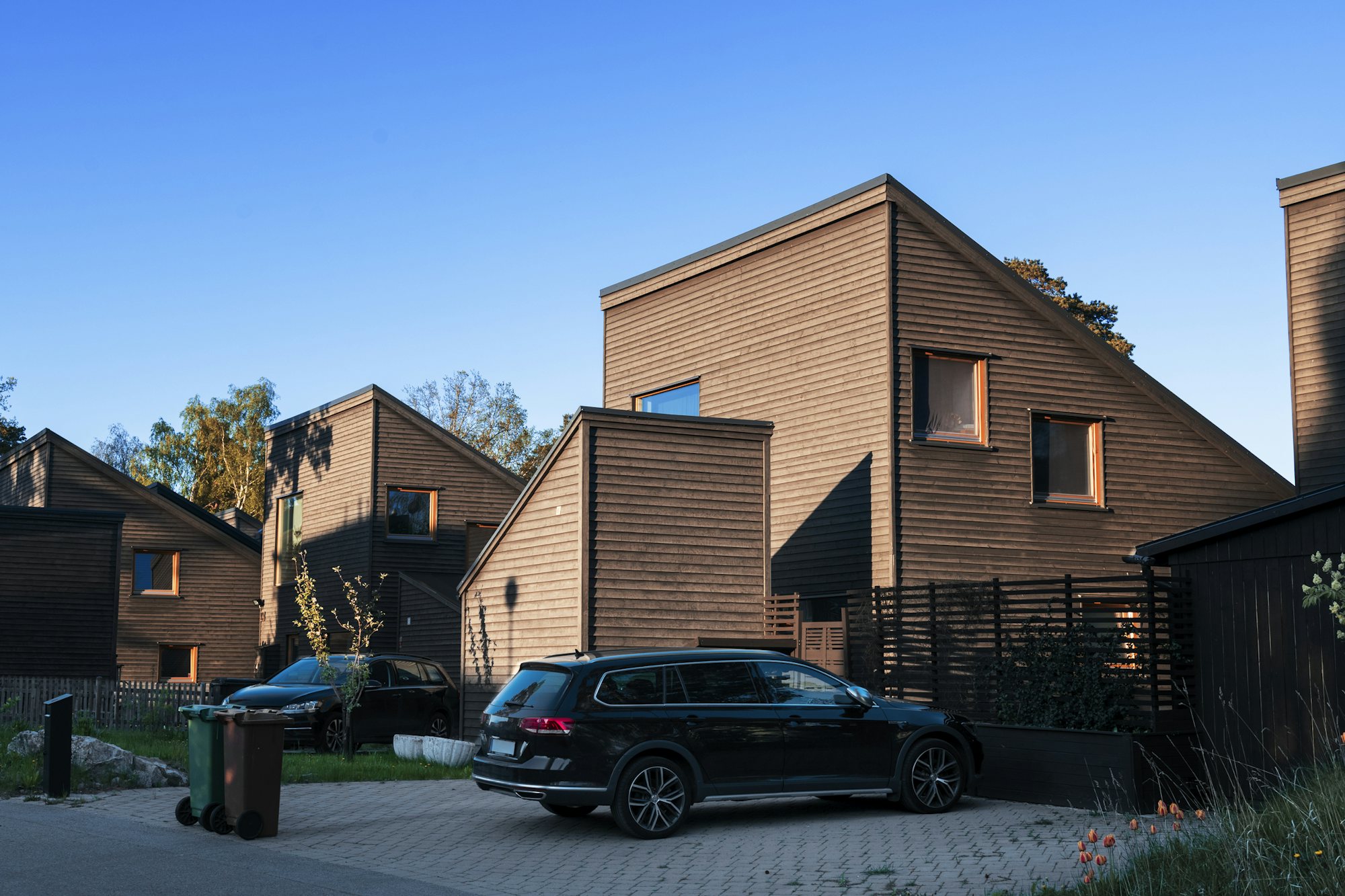 Moderna radhus i trä med bil parkerad på uppfart