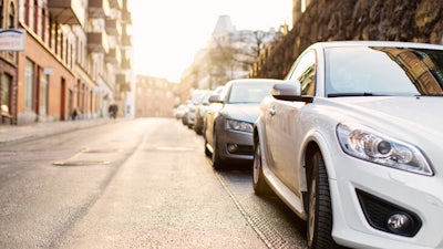 Several cars parked in a straight row on a slope.