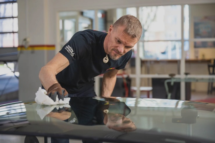 Mees puhastab töökojas autoakent.