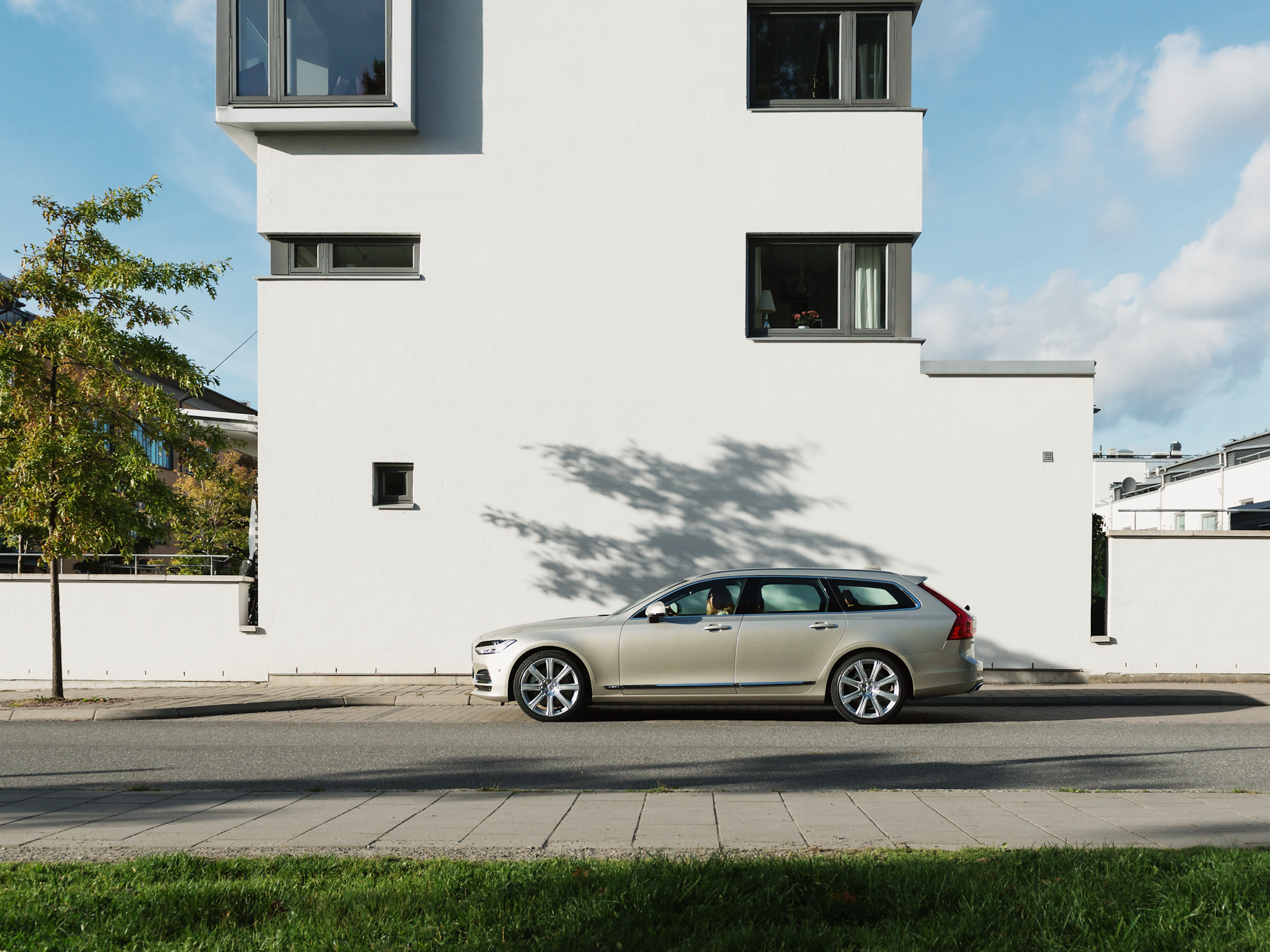 En silverfärgad bil utanför ett vitt bostadshus.