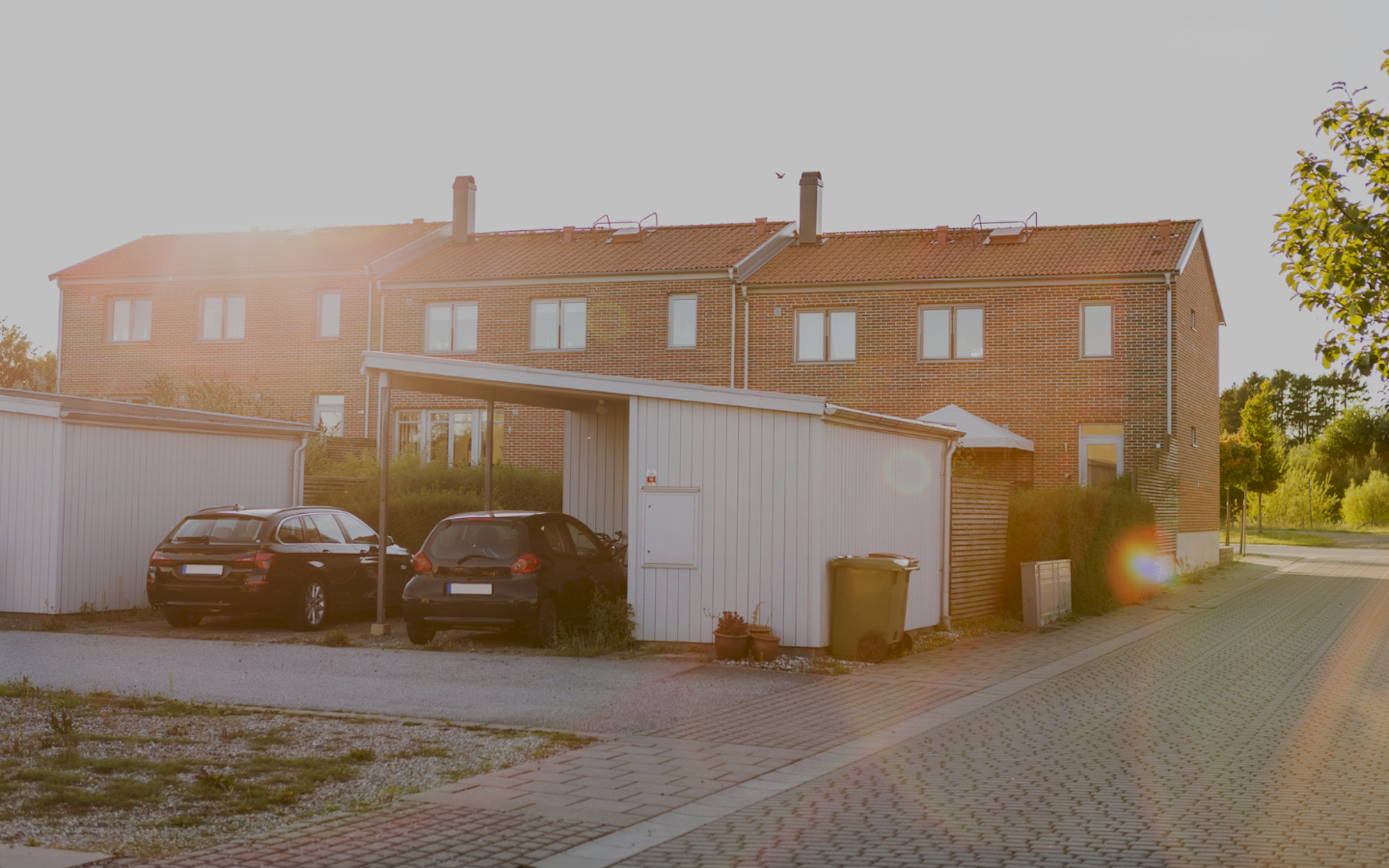 Två svartfärgade bilar parkerade framför ett radhus.