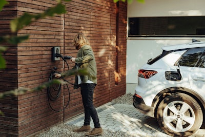Man laddar sin elbil hemma vid garaget
