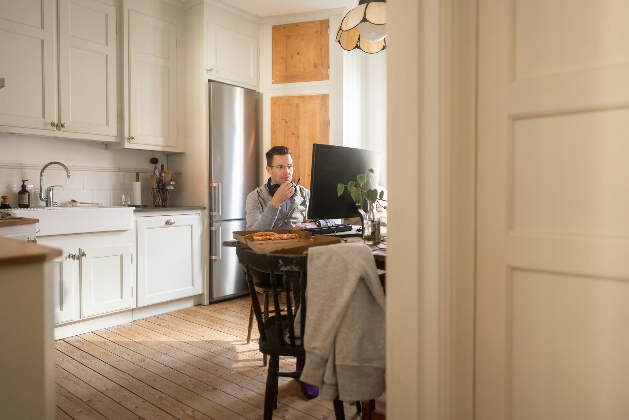 En man arbetar vid en bärbar dator i sitt kök hemma.